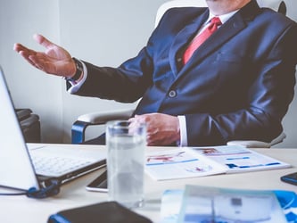 person wearing a suit in an office, sitting at a desk